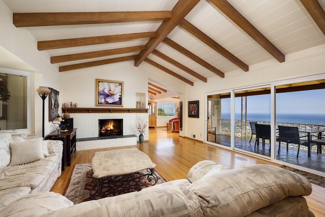 living room with a brick fireplace, vaulted ceiling with beams, hardwood / wood-style flooring, and a water view