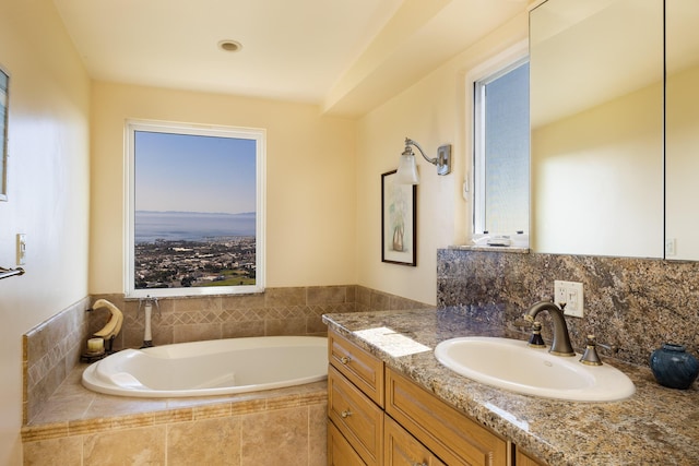 bathroom featuring tiled tub and vanity