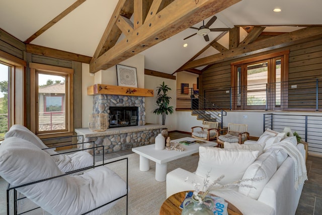 living room featuring beam ceiling, a wealth of natural light, and a stone fireplace