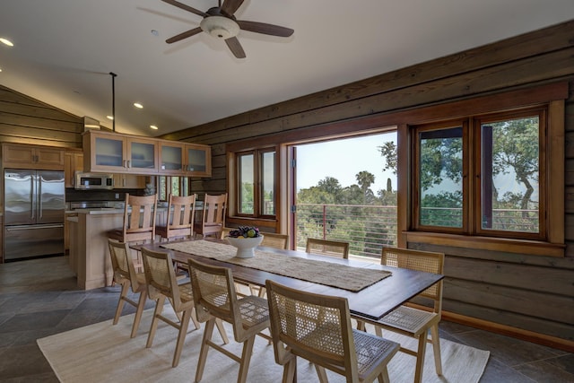 dining area featuring stone finish flooring, wooden walls, vaulted ceiling, and recessed lighting