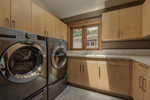 clothes washing area featuring light tile patterned floors, separate washer and dryer, a sink, and cabinet space