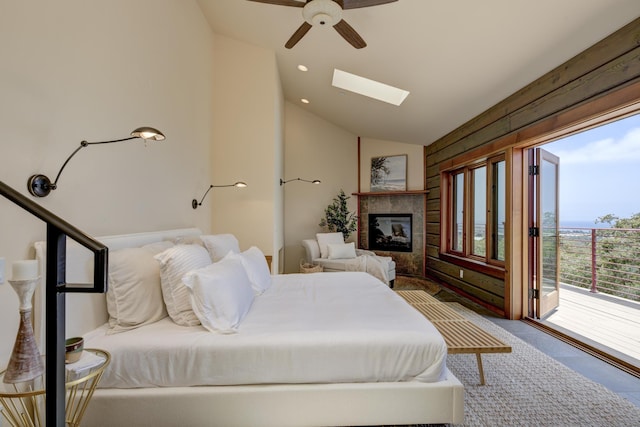 bedroom with a skylight, a ceiling fan, a tiled fireplace, access to outside, and recessed lighting