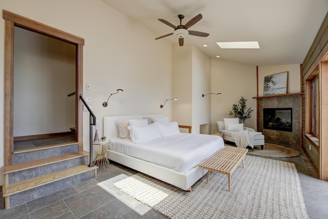 bedroom with ceiling fan, vaulted ceiling with skylight, a fireplace, and recessed lighting