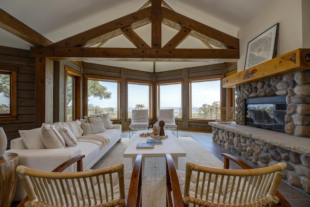 living room with high vaulted ceiling, beamed ceiling, and a stone fireplace