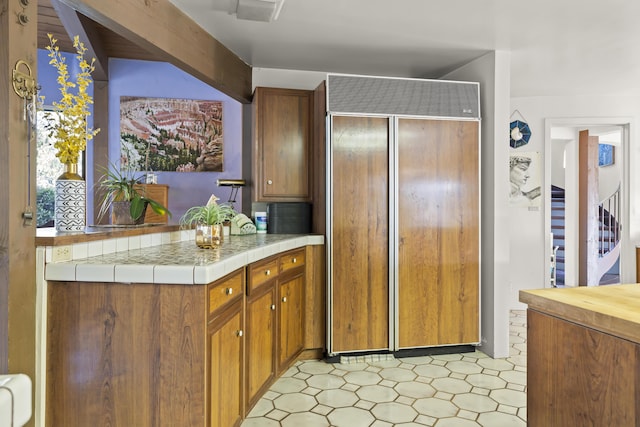 kitchen with paneled built in fridge and tile counters