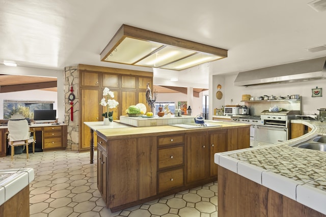 kitchen with electric cooktop, sink, a center island, tile countertops, and range with two ovens