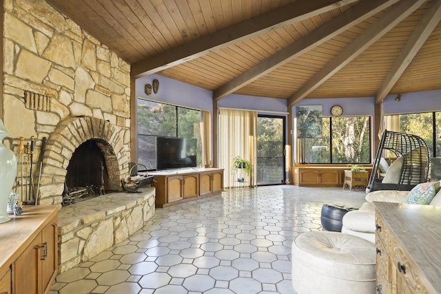 sunroom with beam ceiling, a stone fireplace, and wooden ceiling