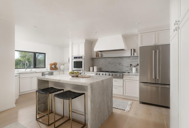 kitchen featuring range hood, a center island, stainless steel appliances, tasteful backsplash, and white cabinetry