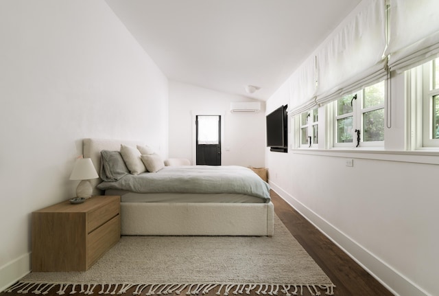 bedroom with vaulted ceiling, dark wood-type flooring, and a wall mounted air conditioner