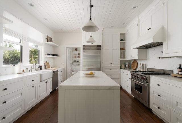 kitchen with a kitchen island, white cabinetry, hanging light fixtures, light stone countertops, and high quality appliances