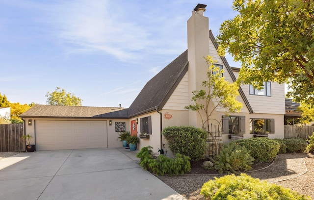 view of front of home featuring a garage, driveway, a chimney, fence, and stucco siding