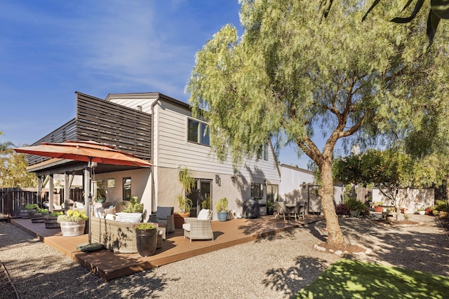 rear view of house with a deck, a fenced backyard, an outdoor living space, and stucco siding