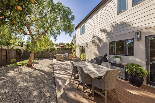 deck featuring outdoor dining space, a fenced backyard, and an outdoor hangout area