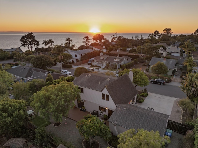 aerial view at dusk with a water view and a residential view