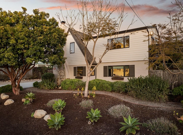 exterior space featuring a shingled roof, a chimney, fence, and stucco siding