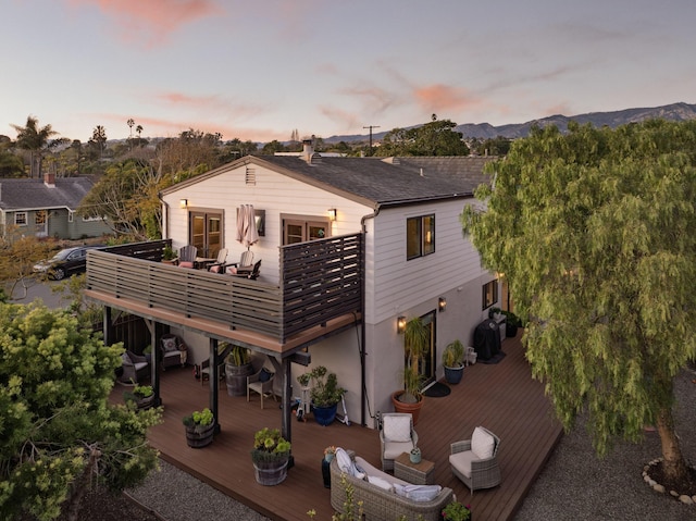 rear view of house with a deck with mountain view and stucco siding