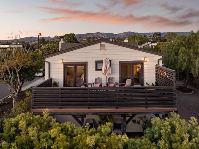 back of house with a chimney, french doors, and a deck with mountain view