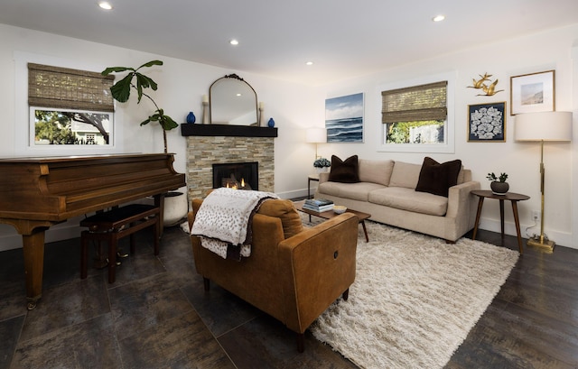 living area featuring baseboards, a stone fireplace, a wealth of natural light, and recessed lighting