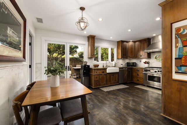 kitchen with visible vents, decorative backsplash, appliances with stainless steel finishes, a sink, and wall chimney range hood