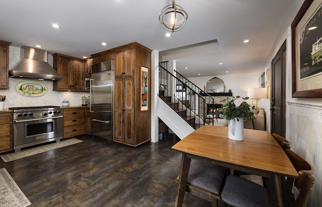 kitchen featuring dark wood-style floors, wall chimney exhaust hood, high quality appliances, backsplash, and recessed lighting