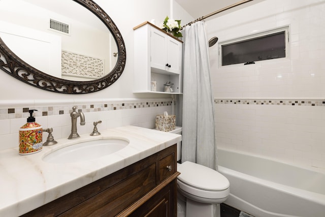 full bathroom with shower / tub combo with curtain, tile walls, visible vents, toilet, and vanity