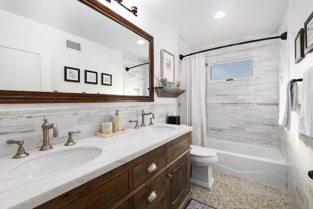 full bathroom with visible vents, shower / bath combo, tile walls, and a sink