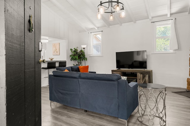 living room featuring plenty of natural light, a chandelier, lofted ceiling with beams, and light wood-type flooring