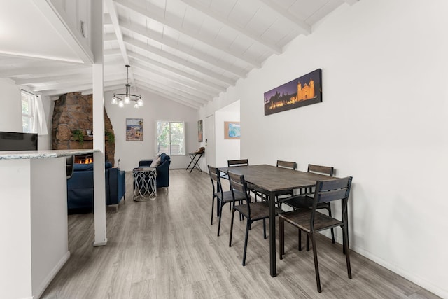 dining space featuring beamed ceiling, high vaulted ceiling, a fireplace, and light hardwood / wood-style floors