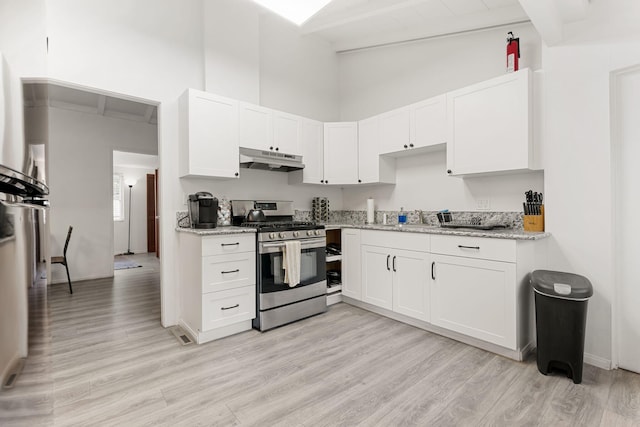 kitchen featuring white cabinetry, stainless steel range with gas stovetop, and light stone counters