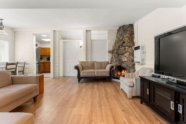 living room with a stone fireplace and light hardwood / wood-style floors