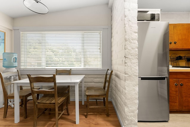 dining room with lofted ceiling and light wood-type flooring