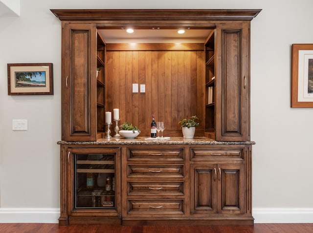 bar with wine cooler, dark hardwood / wood-style floors, and dark stone counters