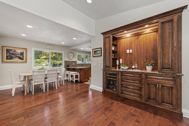 bar with dark hardwood / wood-style floors, sink, and stone counters