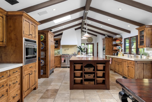 kitchen with beamed ceiling, premium range hood, appliances with stainless steel finishes, and a healthy amount of sunlight