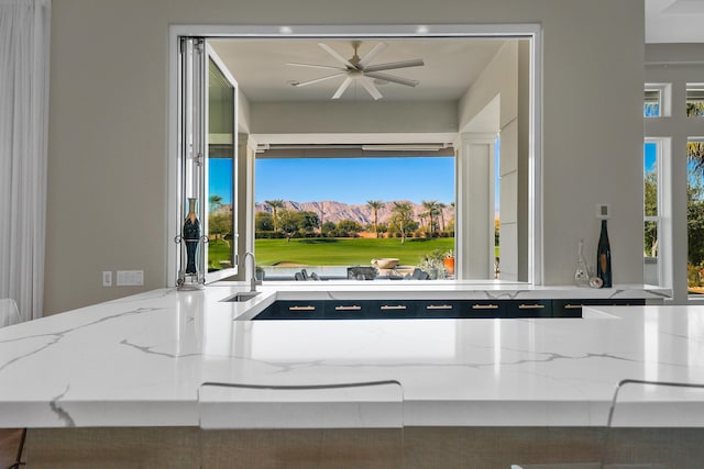 interior details featuring ceiling fan, a mountain view, and light stone counters