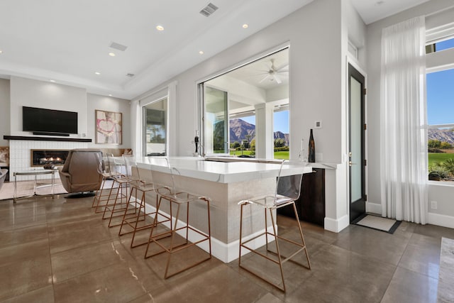 kitchen featuring a mountain view, a kitchen breakfast bar, kitchen peninsula, and a tiled fireplace