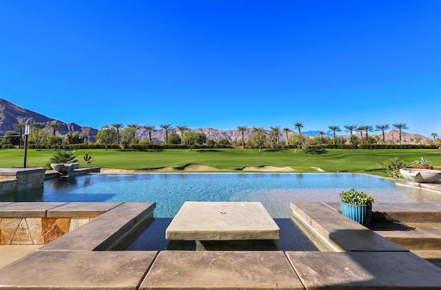 view of swimming pool with a water and mountain view and a lawn