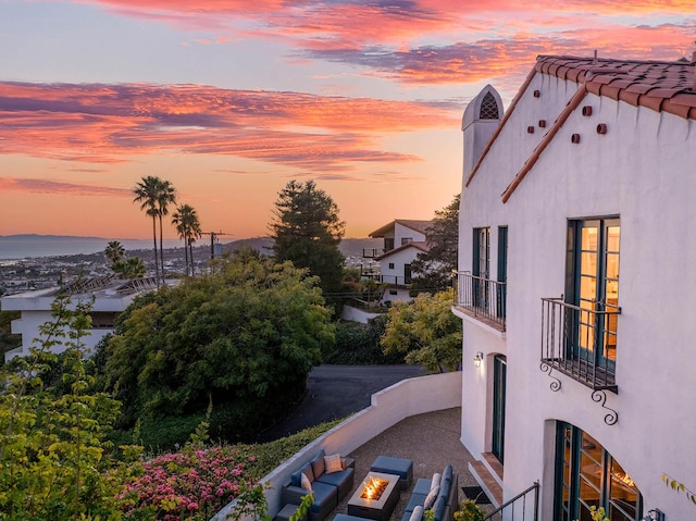 view of side of property featuring stucco siding, a balcony, and an outdoor fire pit