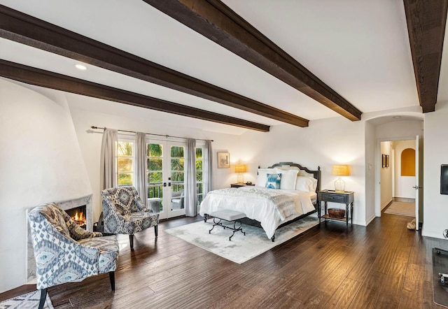 bedroom with beamed ceiling, arched walkways, wood finished floors, and access to outside