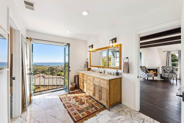 bathroom with recessed lighting, a healthy amount of sunlight, marble finish floor, and a lit fireplace