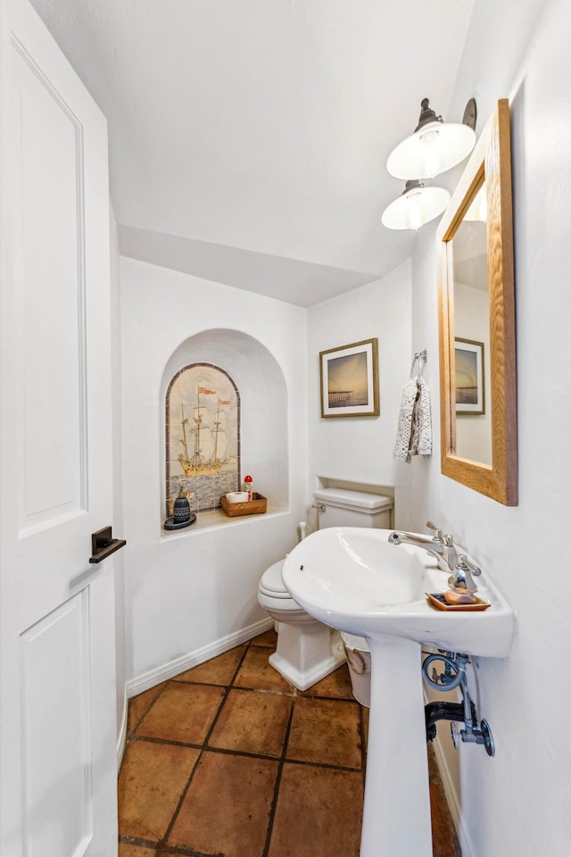 half bathroom featuring baseboards, toilet, and tile patterned flooring