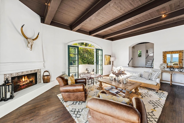 living room featuring wood ceiling, beam ceiling, wood-type flooring, and a warm lit fireplace