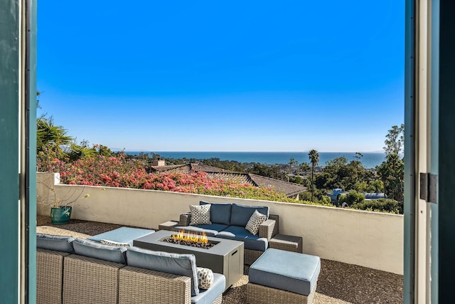 view of patio with an outdoor living space with a fire pit, a balcony, and a water view