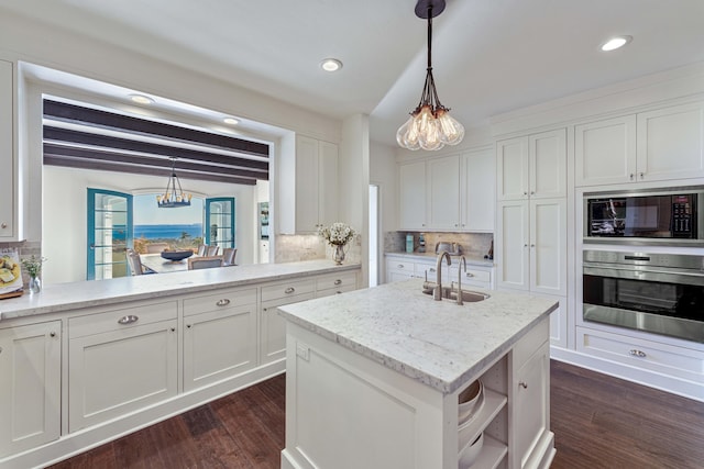 kitchen with a sink, white cabinets, black microwave, and oven