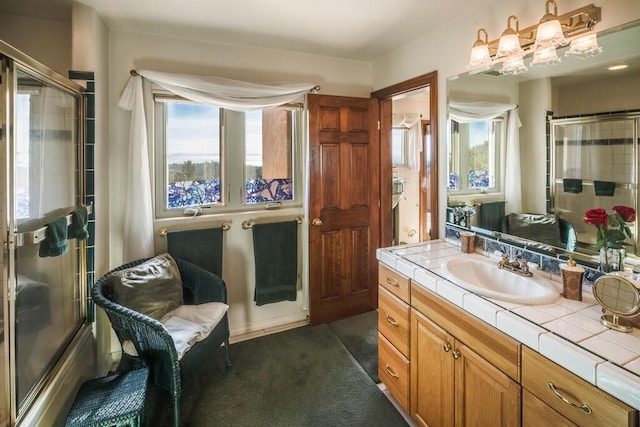 bathroom with vanity, tiled shower, and a wealth of natural light