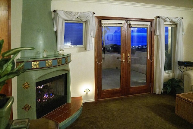 entryway with ornamental molding, dark carpet, a fireplace, and french doors