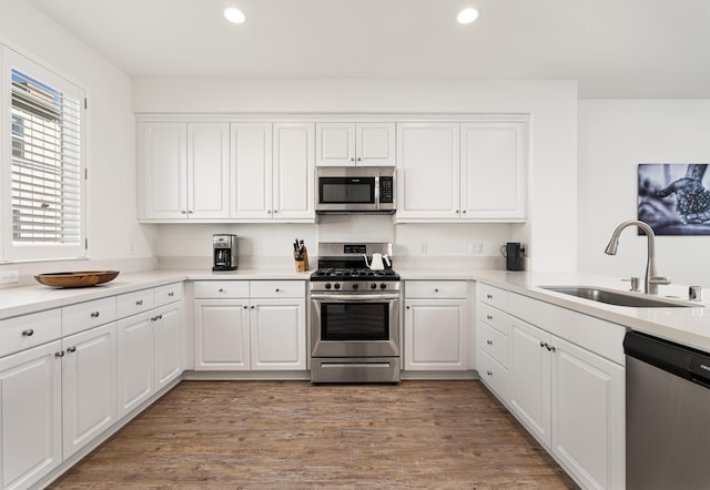 kitchen with white cabinetry, sink, stainless steel appliances, and light hardwood / wood-style floors