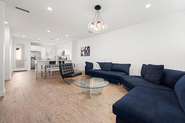 living room with a notable chandelier and light wood-type flooring