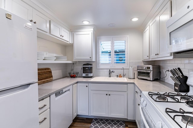 kitchen with tasteful backsplash, sink, white cabinets, and white appliances