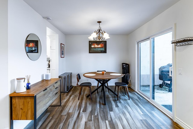 dining space featuring dark wood-type flooring and an inviting chandelier